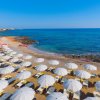 Vista spiaggia con ombrelloni, mare e cielo blu.