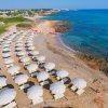 Spiaggia sabbiosa con ombrelloni bianchi e mare turchese.