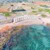 Spiaggia con ombrelloni bianchi vista dall'alto.