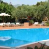 Piscina all'aperto con lettini e ombrellone bianco.