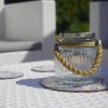 Vaso di vetro con manico in corda su tavolo in vimini.