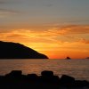 Tramonto sul mare con isole all'orizzonte.