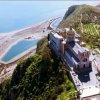 Grande edificio su una collina vicino a una spiaggia e al mare.