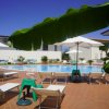 Piscina con lettini e ombrelloni, visibili foglie di banano.