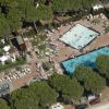 Due piscine circondate da pini e persone.