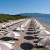 Spiaggia con file di ombrelloni bianchi e marroni.