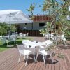 Tavoli e sedie sotto ombrelloni bianchi su terrazza in legno.