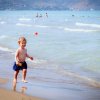 Bambino che corre felice sulla spiaggia vicino all'acqua.