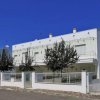 Palazzina bianca moderna con terrazzi e cielo blu.