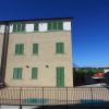 Edificio beige con persiane verdi. Cielo blu.