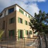 Edificio a tre piani con finestre verdi.