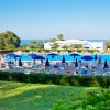 Piscina ampia con ombrelloni blu, vista mare e giardino curato.