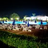 Piscina illuminata di notte, contornata da lettini e ombrelloni blu.