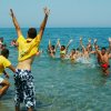 Persone giocano in mare, alcune indossano magliette gialle.