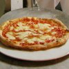 Una pizza margherita su un piatto bianco, posta su un piano di marmo.