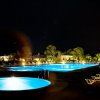Piscina illuminata di notte con lettini.