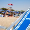 Sdraio blu su una spiaggia con ombrelloni blu e rossi sullo sfondo.