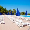 Sdraio con ombrelloni blu accanto a una piscina all'aperto in una giornata soleggiata.