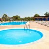 Piscina circolare e grande piscina rettangolare con lettini e ombrelloni blu.
