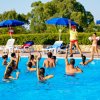 Persone fanno esercizi acquatici in una piscina all'aperto.