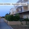 Edificio residenziale con balconi e vialetto in pietra al tramonto.