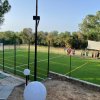 Campo da calcetto recintato con erba sintetica, un gruppo di persone vicino alla recinzione.