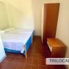 Camera con due letti singoli, armadio e comodino, pavimento in piastrelle rosse.