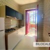 Cucina con frigorifero, piano cottura, e porta aperta verso l'esterno, piastrelle a motivi.
