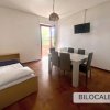 Soggiorno con tavolo, sedie, letto singolo e TV a parete.
