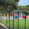 Area giochi all'aperto con scivoli colorati vicino a un campo da calcetto.