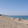 Spiaggia sabbiosa con bagnanti e ombrelloni colorati.