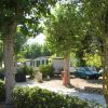 Case mobili tra gli alberi con una macchina parcheggiata vicino e mattoni impilati.