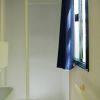 Bagno con doccia, WC e finestra con tendina blu.