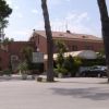 Edificio di un hotel con parcheggio e alberi alti.