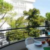 Balcone con tavolo e sedie, vista su alberi e edificio bianco.
