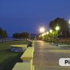 Lungomare illuminato di sera con panchine e lampioni.