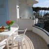 Balcone con tavolo e sedie, vista mare tra gli alberi.