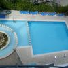 Piscina vista dall'alto con sdraio blu attorno.
