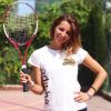 Donna sorridente con racchetta da tennis in campo all'aperto.