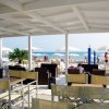 Una terrazza coperta con sedie e tavolini vista mare, ombrelloni sulla spiaggia.