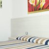 Una camera da letto con copriletto a righe, due quadri floreali alle pareti.