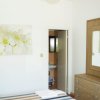 Interno di una camera da letto con armadio, specchio, quadro floreale e porta sul bagno.