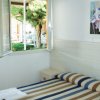 Camera con letto matrimoniale a righe, finestra aperta, dipinto di fiori e farfalle.