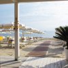 Spiaggia con ombrelloni bianchi e gialli, vista dal patio coperto.
