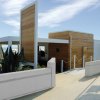 Un edificio moderno in legno sulla spiaggia con bandiere sventolanti e un'area giochi colorata.