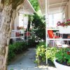 Un patio ombreggiato con piante fiorite, sedie arancioni e tavolini bianchi.