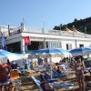 Spiaggia affollata con ombrelloni blu e bianchi.