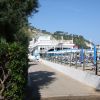 Sentiero alberato vicino a una spiaggia con ombrelloni.