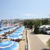 Spiaggia con ombrelloni blu, vicino a un sentiero alberato.