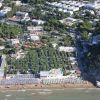 Veduta aerea di una spiaggia con ombrelloni e edifici circostanti.